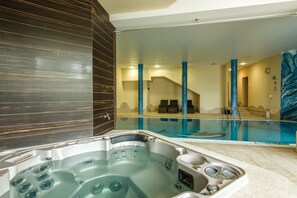 A modern indoor swimming pool with a hot tub, blue pillars, and a view of the pool area. - Dziki Potok (Karpacz)