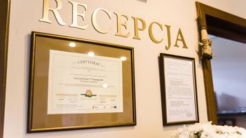 Una pared con la palabra "RECEPTJA" y dos documentos enmarcados.