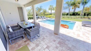 An outdoor patio with a pool, wicker furniture, and a view of the surrounding landscape.