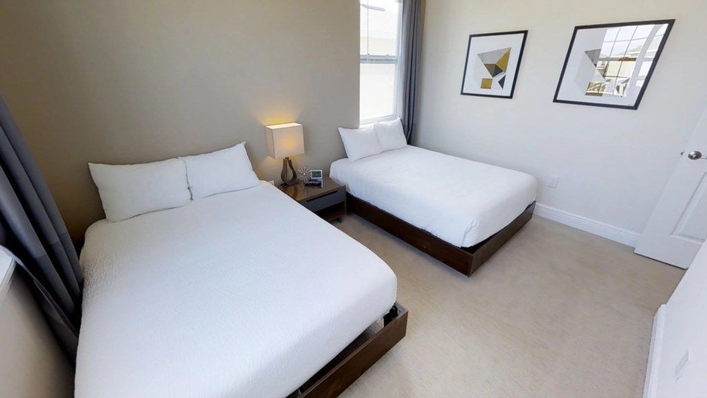 Une chambre d’hôtel avec deux lits simples, une table de chevet avec une lampe et une fenêtre avec des rideaux.