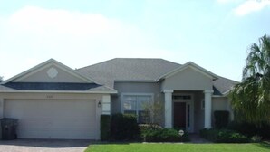 A single-story house with a garage, a front door, and a small front yard with grass and a palm tree. - Ahr137 - Tuscan Hills - 4 Bed 3 Baths Villa (Davenport)