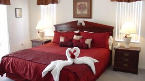 A neatly made bed with red bedding and pillows, a wooden headboard, two bedside tables with lamps, and a framed picture on the wall. - Ahr137 - Tuscan Hills - 4 Bed 3 Baths Villa (Davenport)