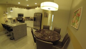 A modern kitchen with a central island, stainless steel appliances, and a dining area with a round table and chairs. - Aco63664 - Serenity - 3 Bed 3 Baths Townhouse (Clermont)