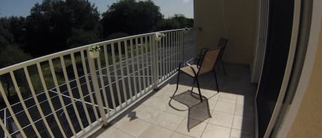 A balcony with a white railing, a chair, and a potted plant.