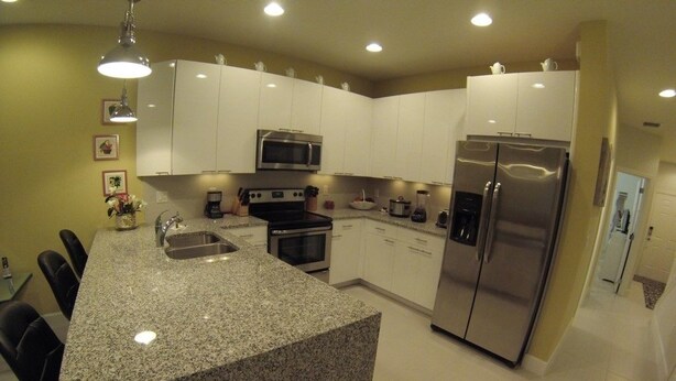 A modern kitchen with granite countertops, stainless steel appliances, and white cabinetry. - Aco63664 - Serenity - 3 Bed 3 Baths Townhouse (Clermont)