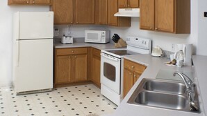 A compact kitchen with wooden cabinets, a white refrigerator, a microwave, a stove, and a sink. - Ip60179 - Silver Creek - 4 Bed 3 Baths Villa (Clermont)
