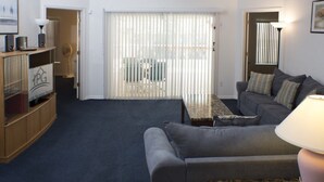 A living room with a grey sofa, a coffee table, and a TV stand with speakers. - Ip60179 - Silver Creek - 4 Bed 3 Baths Villa (Clermont)