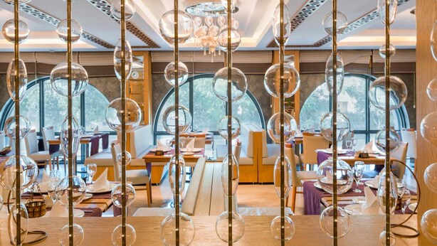 A restaurant with a modern interior, featuring hanging glass spheres and a view through large windows. - Plus Hotel Setif (Setif)