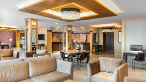 A spacious hotel lobby with leather sofas, a round dining table, and a chandelier. - Plus Hotel Setif (Setif)