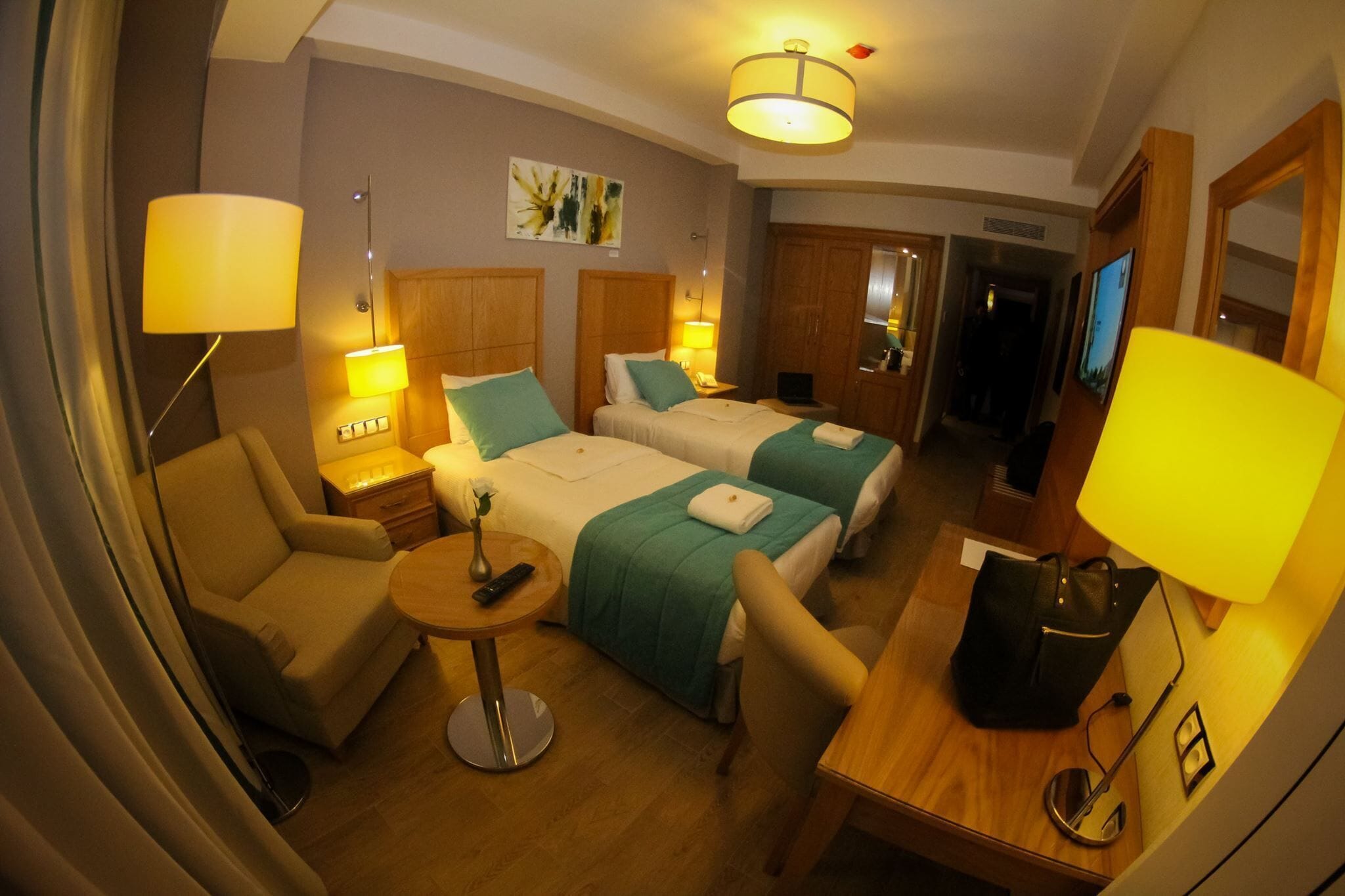 Une chambre d’hôtel avec deux lits, un canapé, une petite table et un téléviseur.