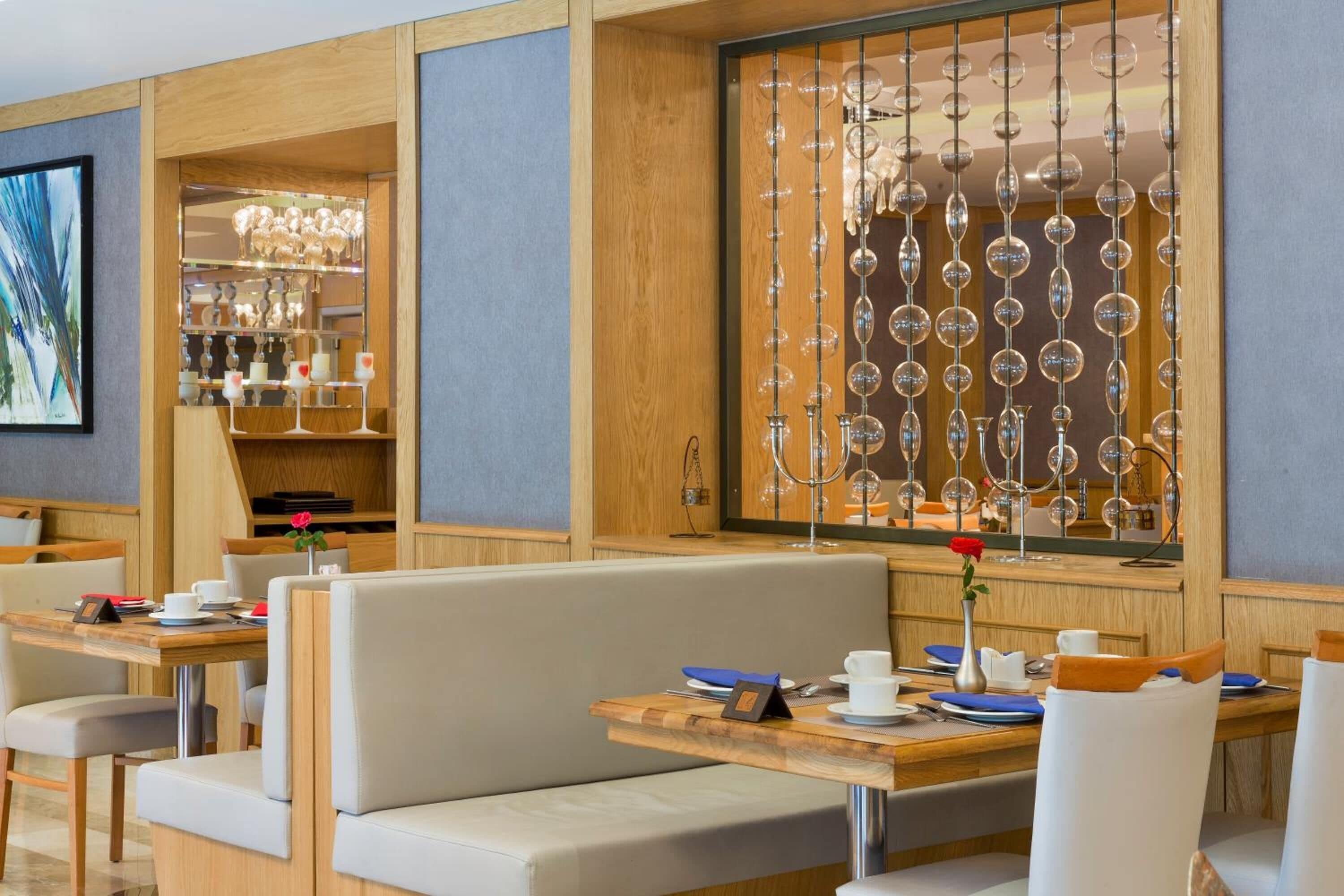 Un comedor moderno con mobiliario de madera, una vitrina de copas de vino y un conjunto de asientos.