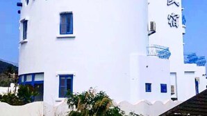 A white building with a unique architectural design, featuring circular windows and a vertical sign with Chinese characters. - Fuyue sea View (Taitung)