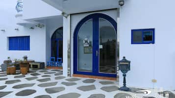 Un edificio con fachada blanca, puerta azul y patio con diseño de piedra.