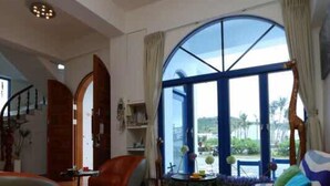 A spacious living room with a large window, a sofa, a coffee table, and a staircase leading to another level. - Fuyue sea View (Taitung)