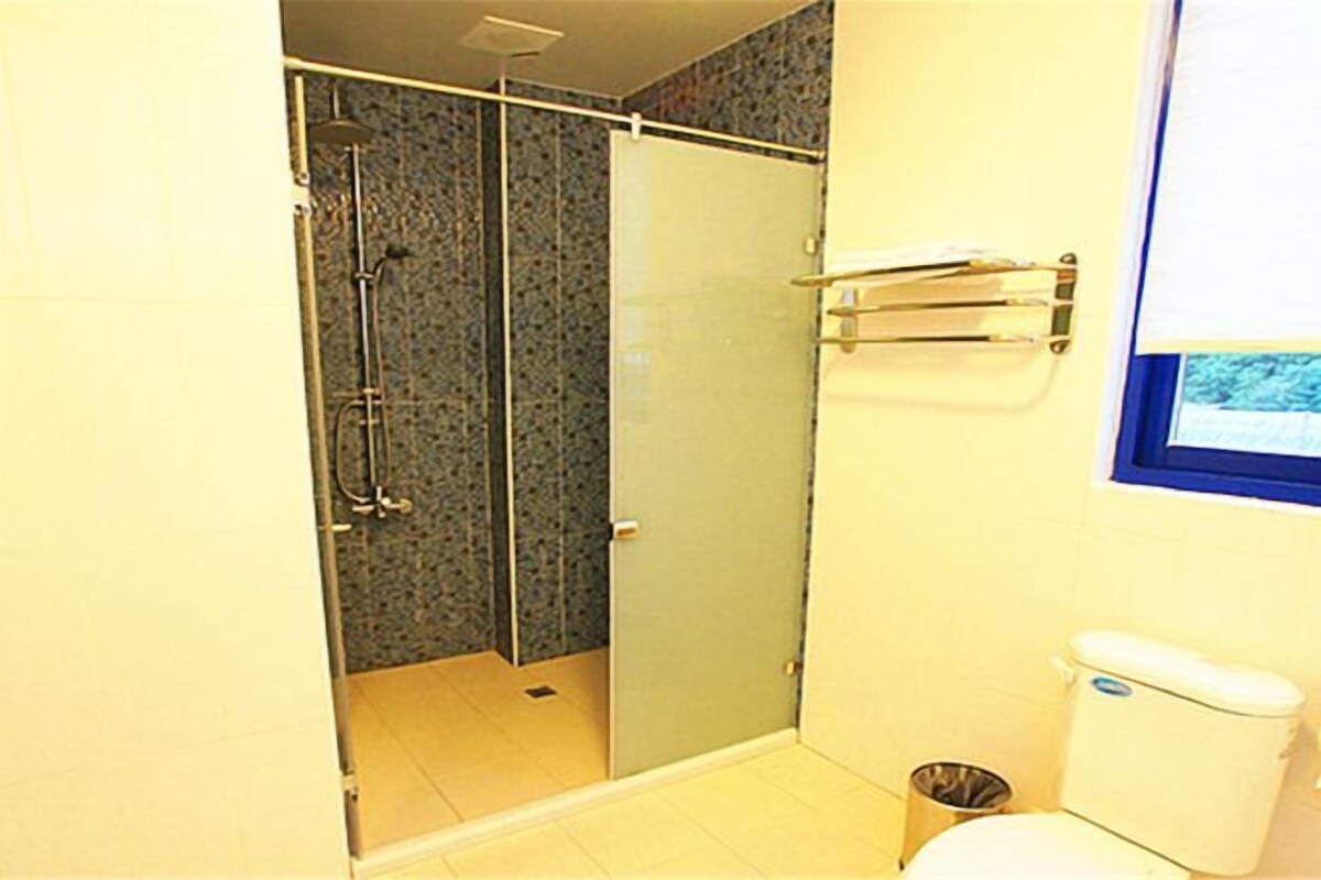 A bathroom with a glass-enclosed shower, a toilet, and a towel rack.