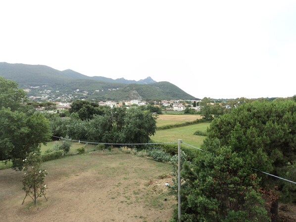 Paisaje rural con un pueblo, montañas y vegetación.
