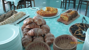 Un tavolo per buffet con diversi prodotti da forno, tra cui pane, pasticcini e una torta.