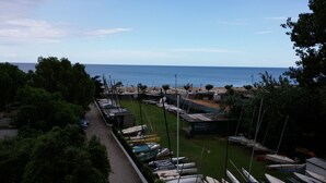 A marina with boats docked, a path leading to the beach, and a view of the sea. - Hotel Le Pleiadi (San Felice Circeo)