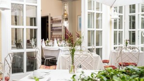 Un comedor con mesas dispuestas para dos, manteles blancos y sillas con cojines escoceses.