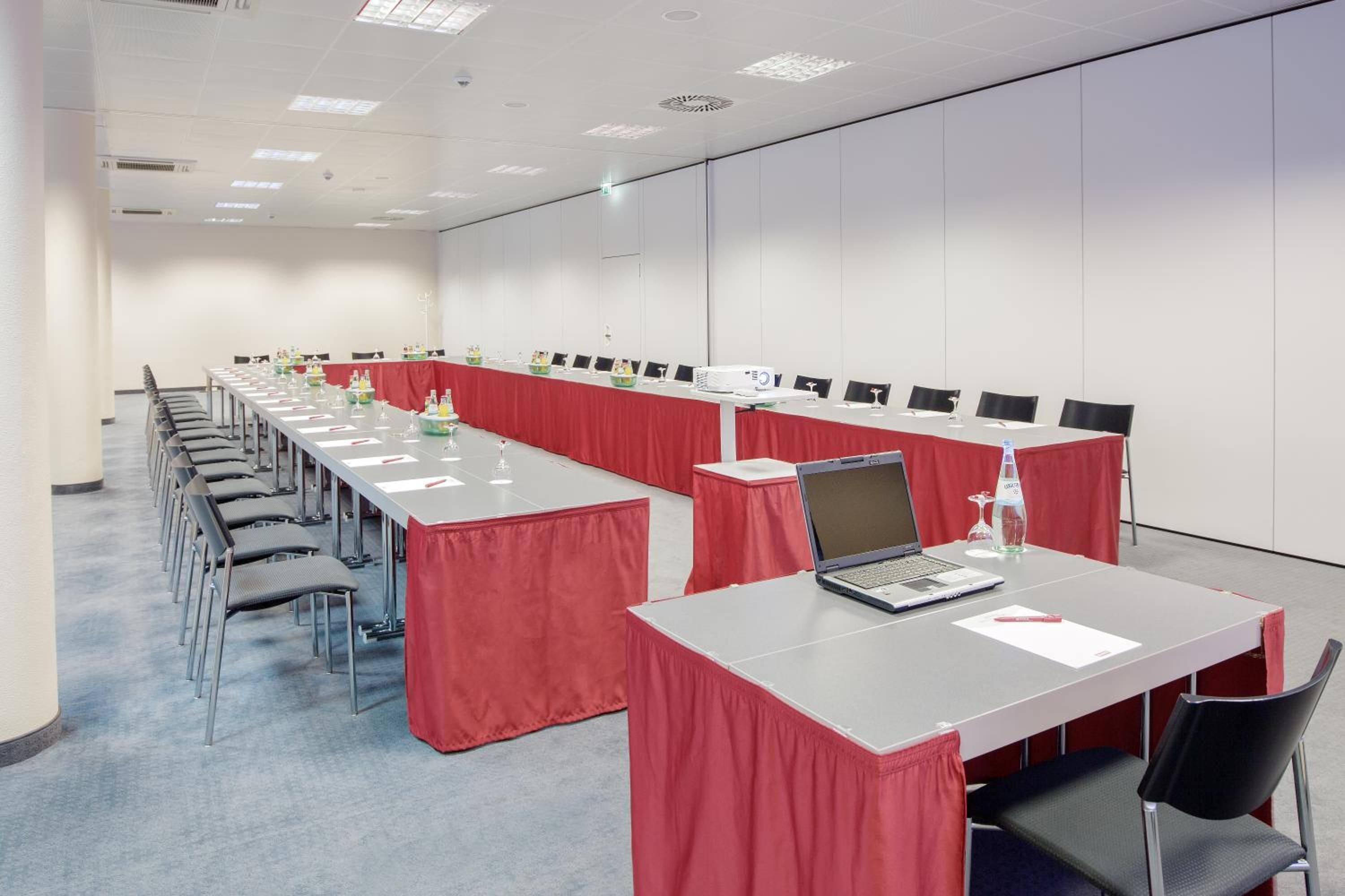 A conference room with long tables, chairs, and laptops.