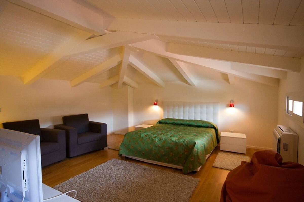 Ein Schlafzimmer mit einem Bett, zwei Nachttischen, einem Schreibtisch, einem Stuhl und einem Fernseher.