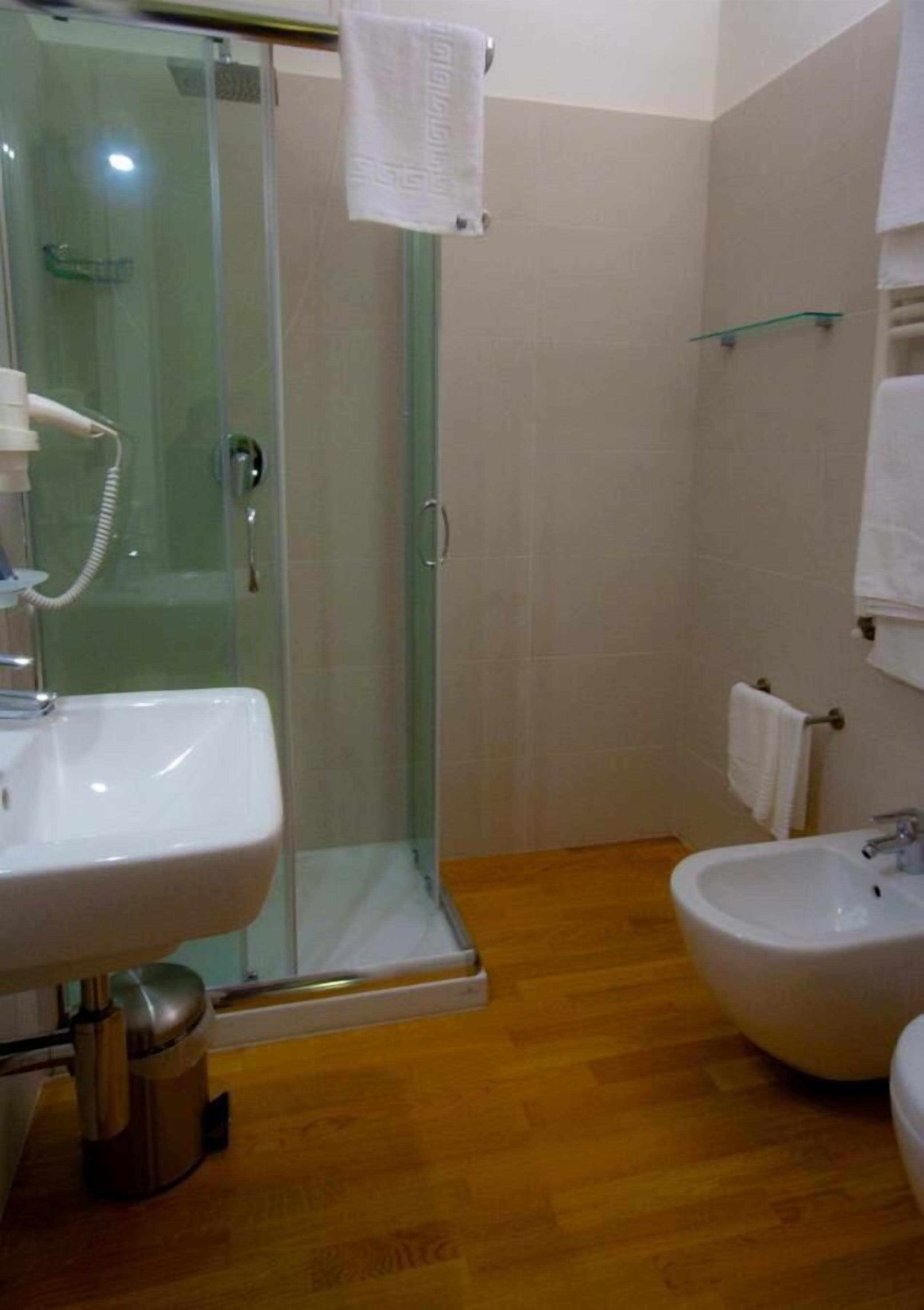Un baño con ducha de vidrio, lavamanos y bidé.