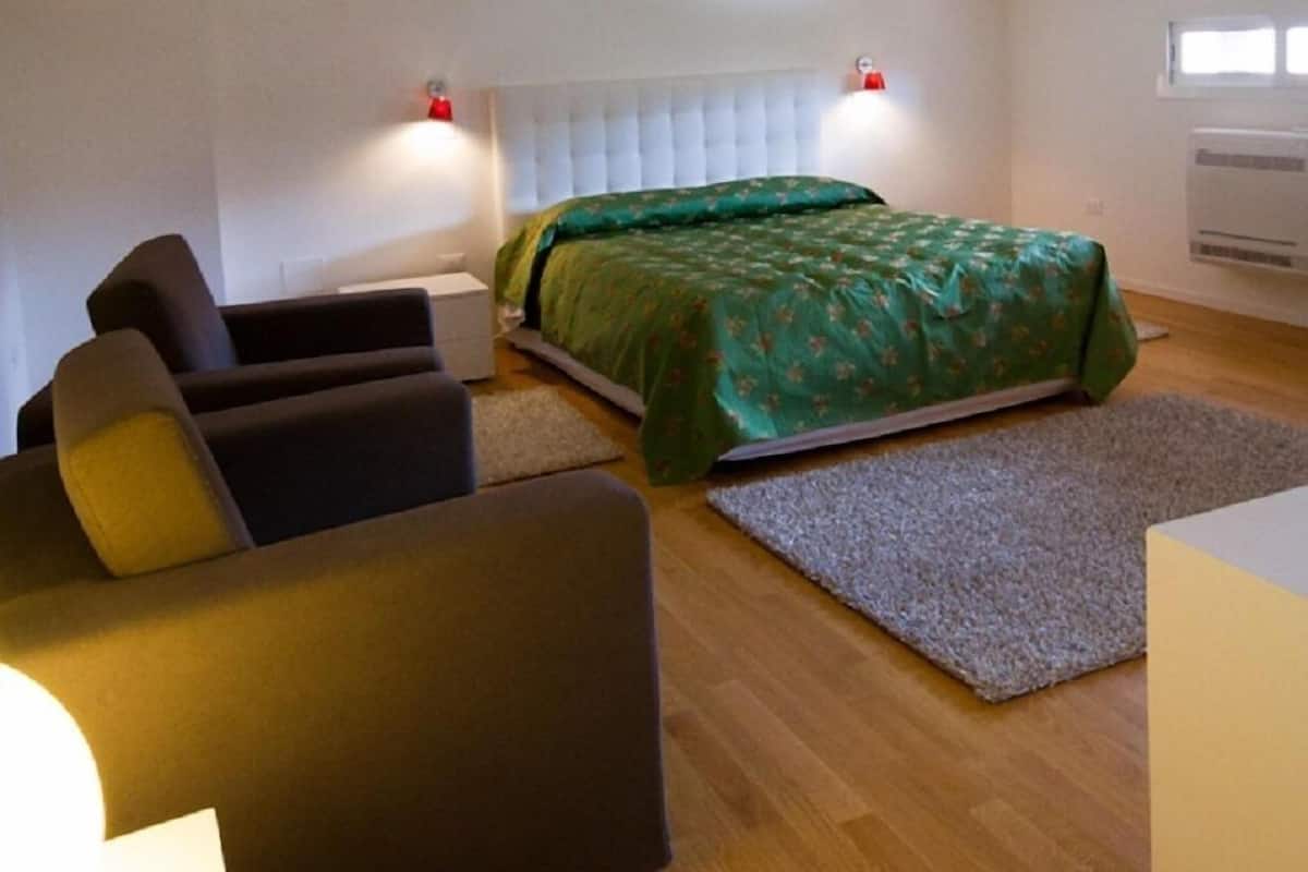 Ein Schlafzimmer mit Bett, Sofa, Nachttisch und Fenster.
