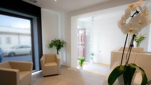 A modern hotel lobby with a large window, two sofas, and a potted orchid. - Hotel Muraglie (Vibo Valentia)
