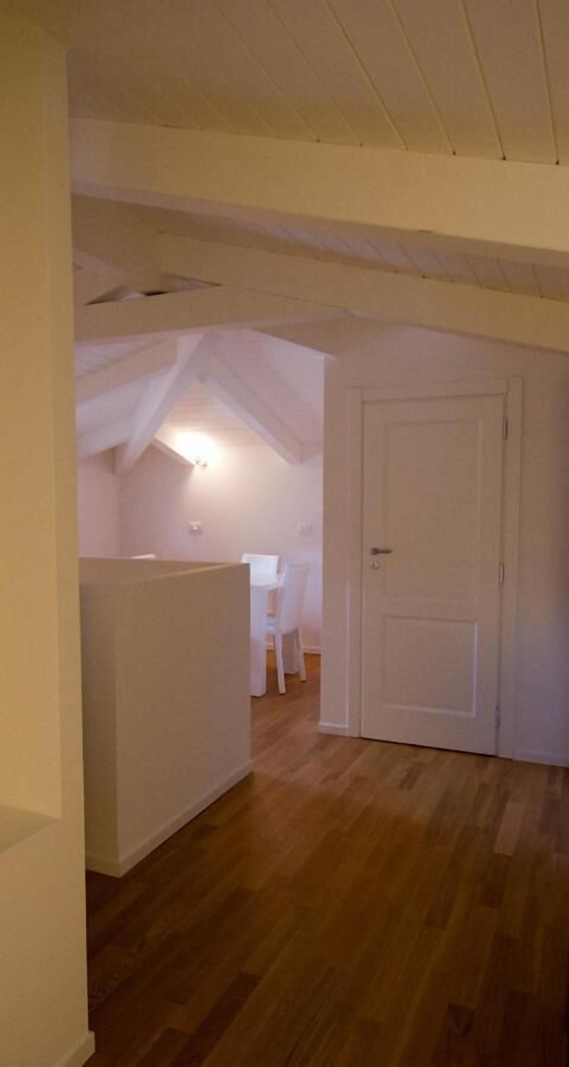 A room with wooden flooring, a white door, and a small white table with chairs.