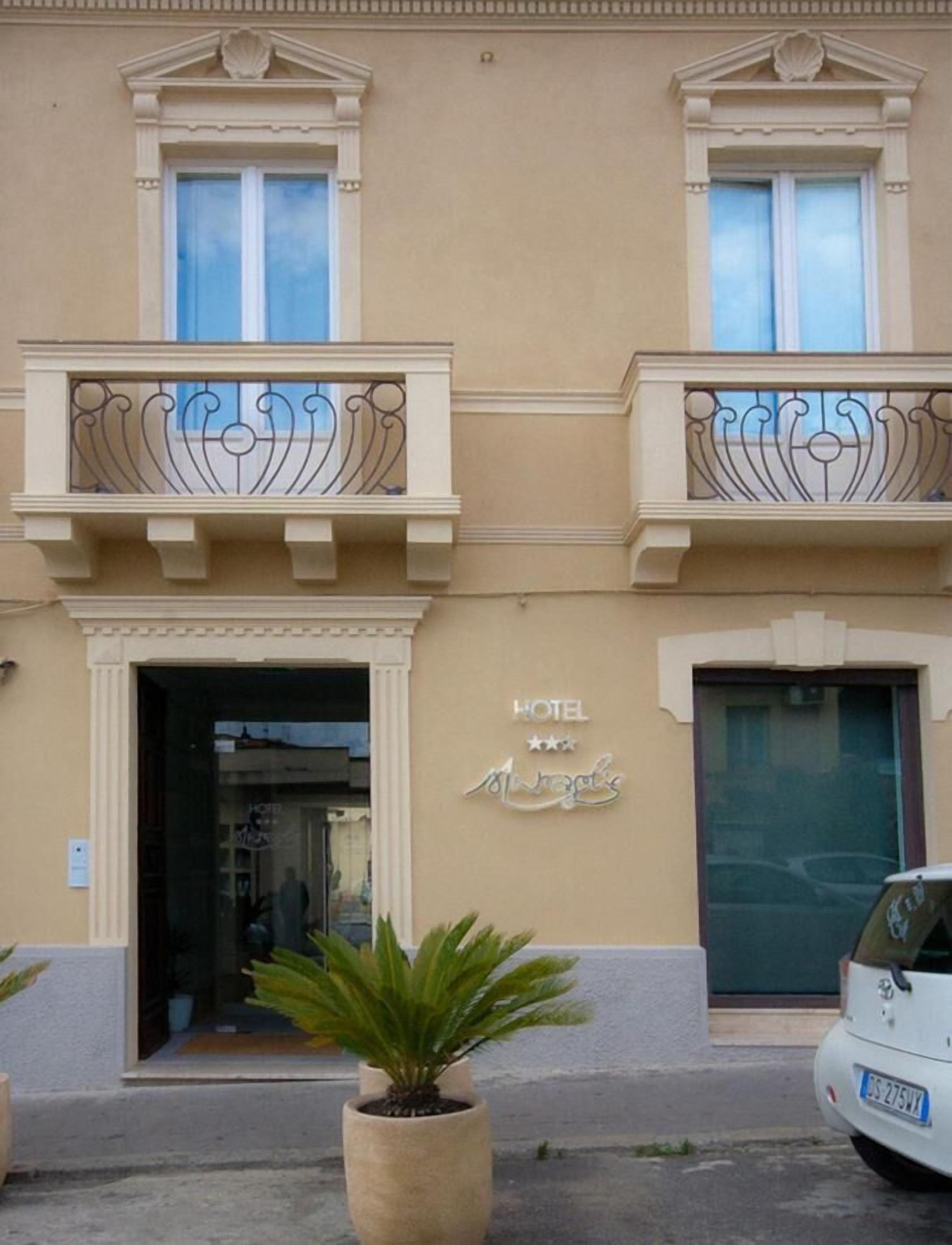 La façade d’un hôtel présente un style architectural classique, avec deux balcons dotés de garde-corps en métal ouvragé et une enseigne indiquant qu’il s’agit d’un hôtel trois étoiles.
