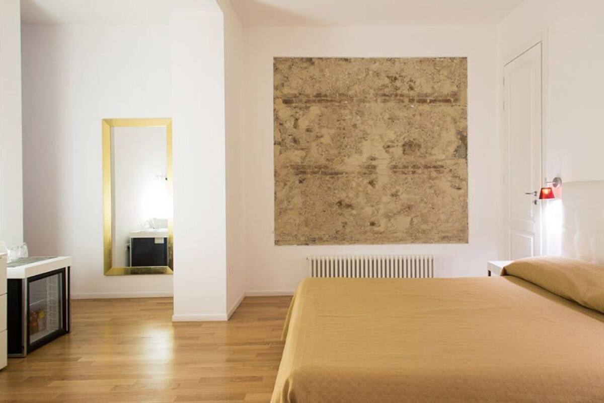 Ein Schlafzimmer mit einem Bett, einem Spiegel, einer Heizung und einer Tür.