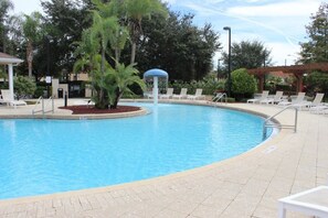 Piscina com espreguiçadeiras e um gazebo.