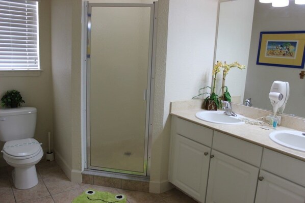 A bathroom with a toilet, a shower, a sink, and a mirror.