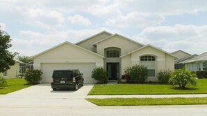 A single-story house with a garage, a driveway, and a front lawn. - Ahr226 - Rolling Hills Estates - 4 Bed 3 Baths Villa (Kissimmee)