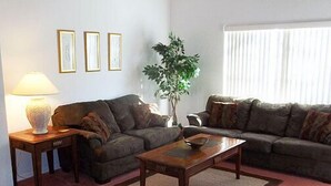 A living room with two sofas, a coffee table, a lamp, and a potted plant. - Ahr226 - Rolling Hills Estates - 4 Bed 3 Baths Villa (Kissimmee)