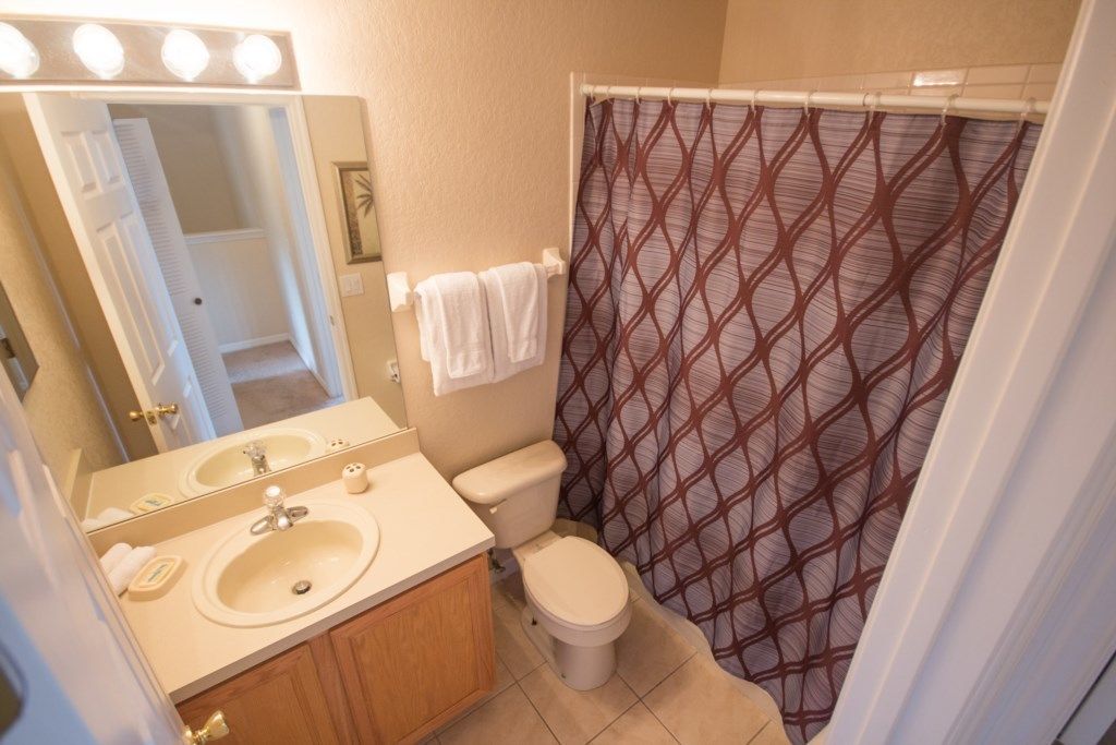 Un baño con tocador, dos lavamanos, inodoro y cortina de ducha.