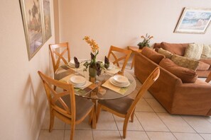 A dining area with a glass table, wooden chairs, and a brown sofa. - Ip60296 - Regal Palms Resort & Spa - 4 Bed 3 Baths Townhome (Davenport)