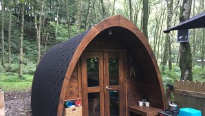 Una cabaña de madera tipo A con una puerta, una mesita y un banco.