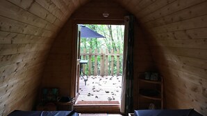 Una cabaña de madera con techo inclinado y un porche que da a una terraza.