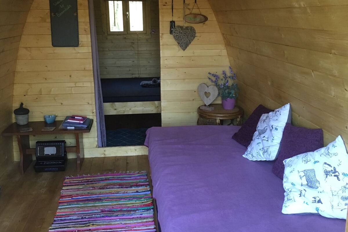 Un dormitorio de cabaña acogedor con cama, alfombra colorida y un cartel de bienvenida.