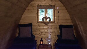Una cabaña acogedora con dos camas, una decoración con forma de corazón en la pared y una mesita con un farol.