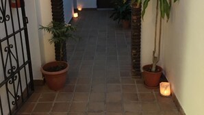An arched entrance to a courtyard with tiled flooring, potted plants, and a gate. - Hostal Restaurante Casa Ríos (Tarifa)