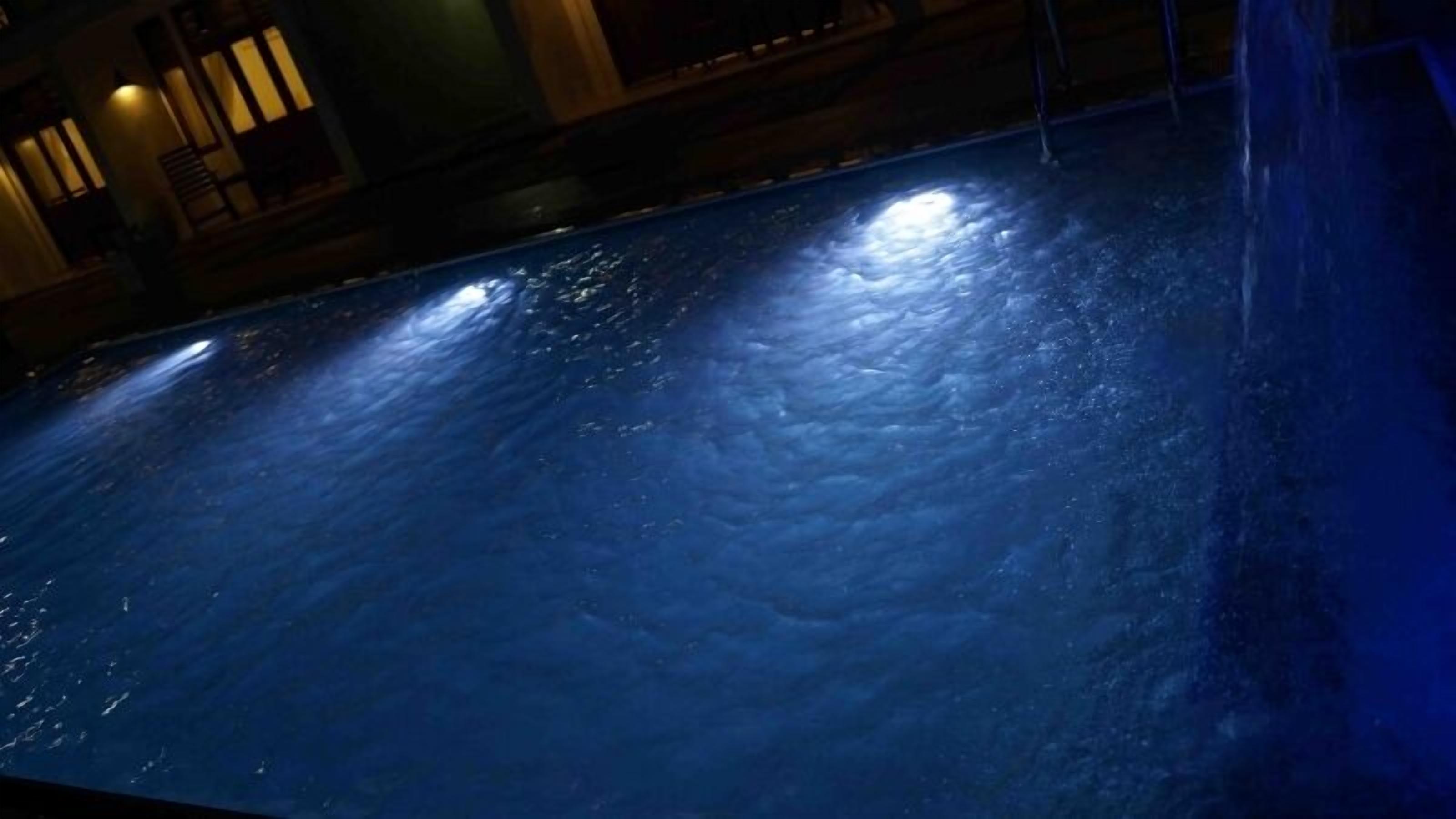 Una piscina con superficie azul oscuro y reflejo de luces.
