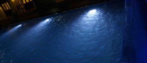 Una piscina con superficie azul oscuro y reflejo de luces.