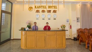 A hotel reception desk with a clock, a fire extinguisher, and a sign indicating the hotel name. - Kantel Hotel (Mandalay)