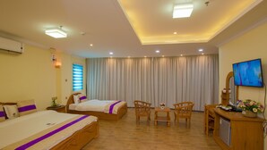 A hotel room with two beds, a desk, chairs, a television, and a small refrigerator. - Kantel Hotel (Mandalay)