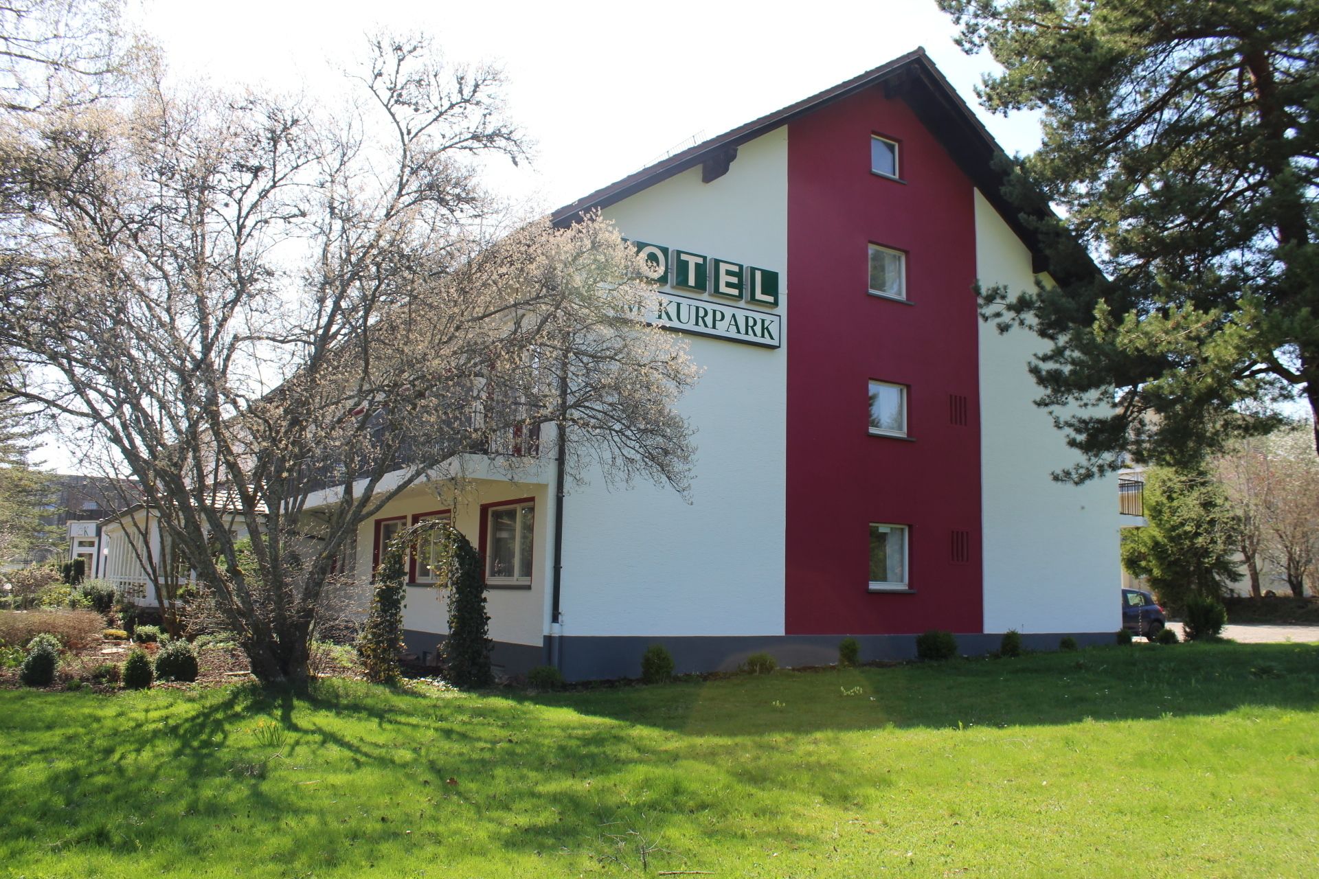 Ein zweigeschossiges Hotel mit roter und weißer Fassade, einem sichtbaren Eingang und einem gepflegten Rasen.