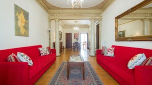 A spacious living room with red sofas, a chandelier, and a large mirror. - Verdi (Florence)