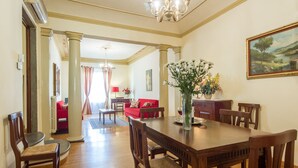 A dining area with a wooden table and chairs, a vase with flowers, and a painting on the wall. - Verdi (Florence)