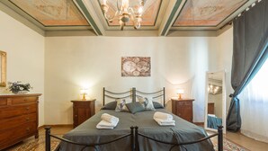 A bedroom with a bed, two nightstands, a dresser, a mirror, and a chandelier. - Verdi (Florence)
